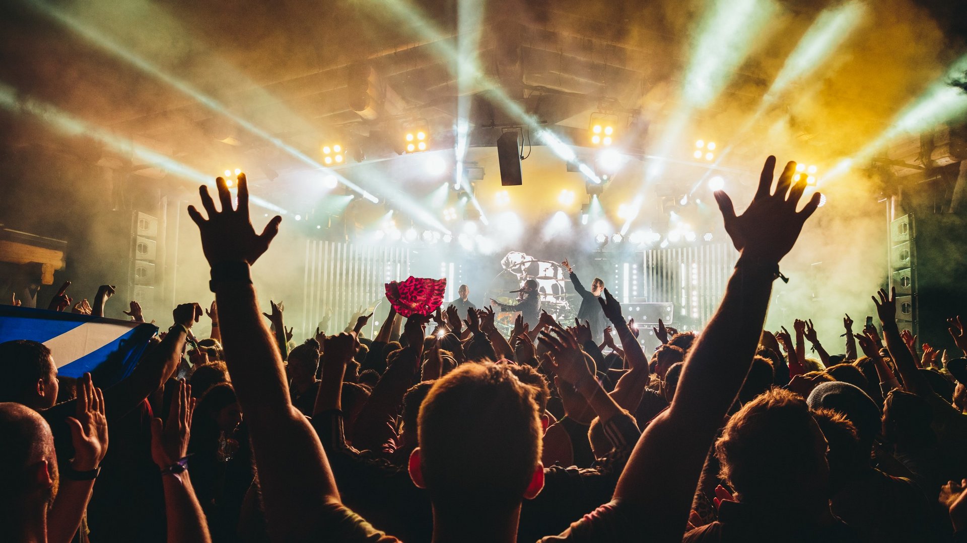 Live-Konzert Atmosphäre Menschenmenge bei einem Konzert hebt die Hände in die Luft während einer Live-Performance mit beeindruckender Bühnenbeleuchtung.